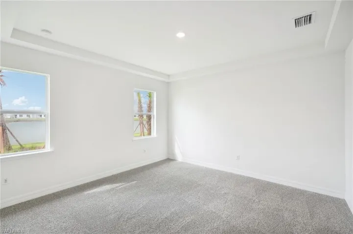 Carpeted empty room featuring a tray ceiling