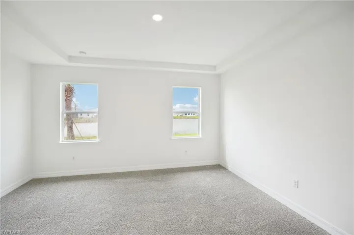 Carpeted spare room featuring a raised ceiling