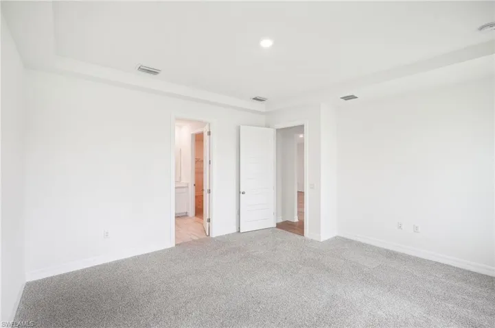 Unfurnished bedroom with light colored carpet and ensuite bath