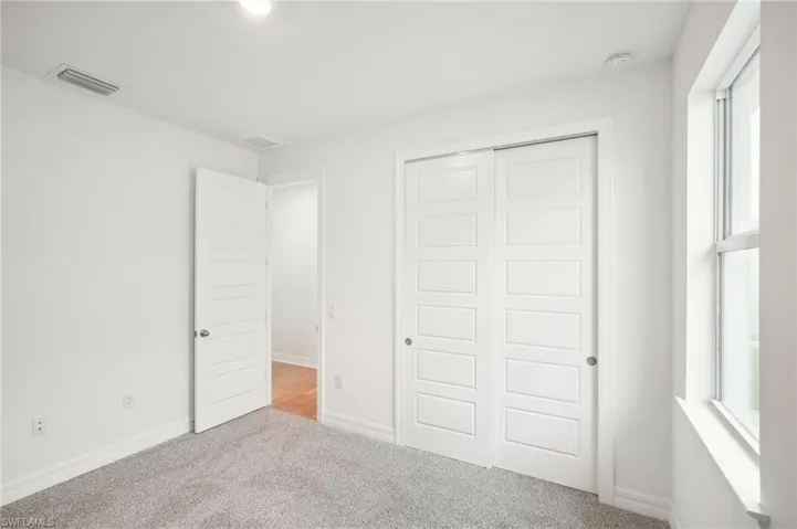 Unfurnished bedroom featuring light colored carpet and a closet