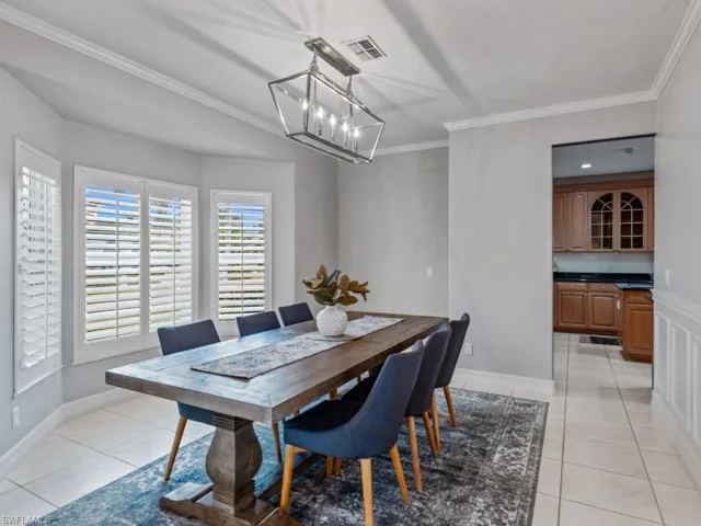 Dining room with crown molding, light tile patterned flooring, and a chandelier