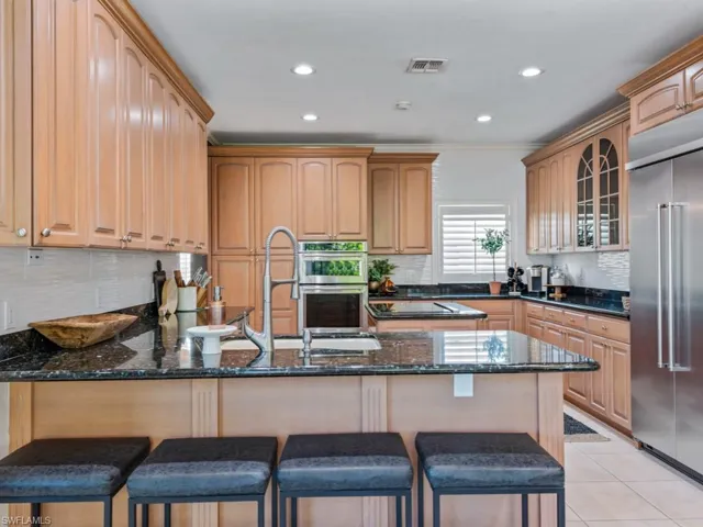 Kitchen with stainless steel appliances, a peninsula, dark stone countertops, glass insert cabinets, and backsplash