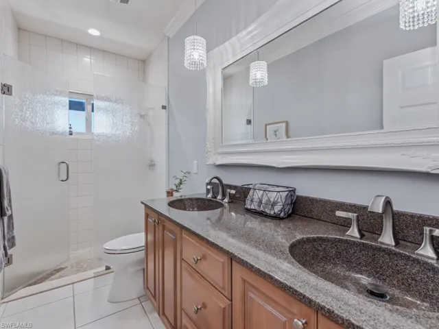 Bathroom featuring a stall shower, double vanity, and tile patterned flooring
