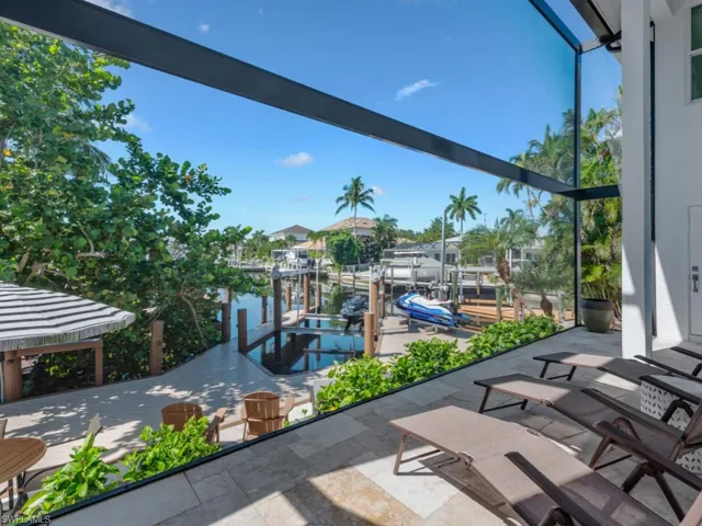 View of patio with boat lift, a boat dock, and a water view