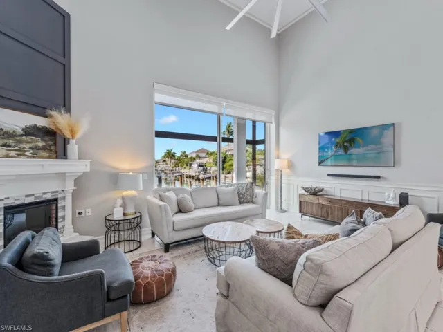 Living area with a high ceiling, a glass covered fireplace, a wainscoted wall, and crown molding
