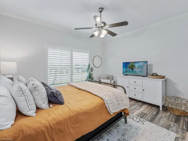 Bedroom featuring ornamental molding, wood finished floors, and a ceiling fan
