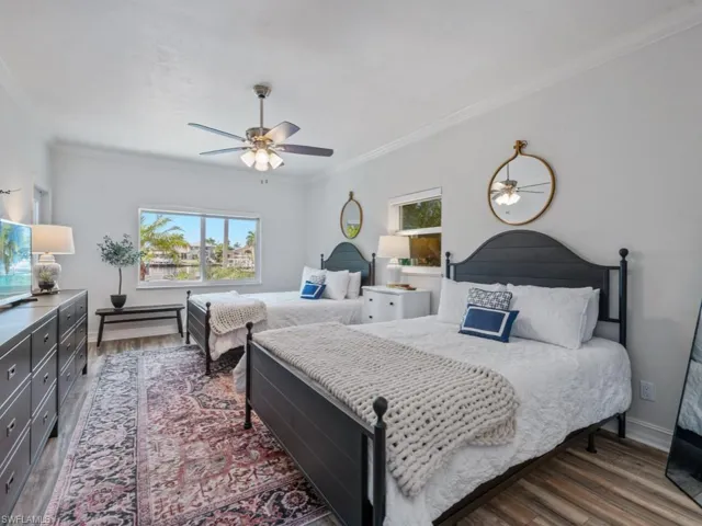 Bedroom with multiple windows, wood finished floors, crown molding, and a ceiling fan