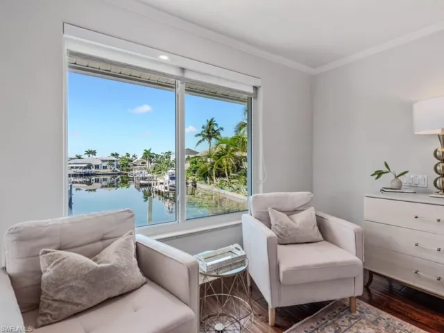 Master bedroom sitting  area with crown molding, wood finished floors, and a water view