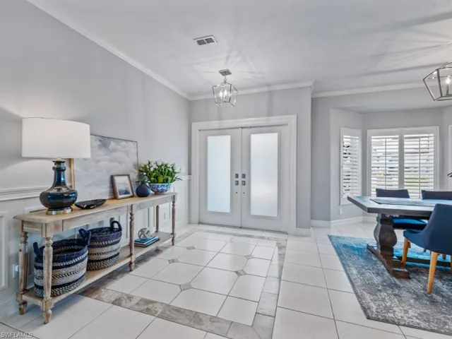 Foyer entrance featuring french doors, ornamental molding, a chandelier, and light tile patterned flooring