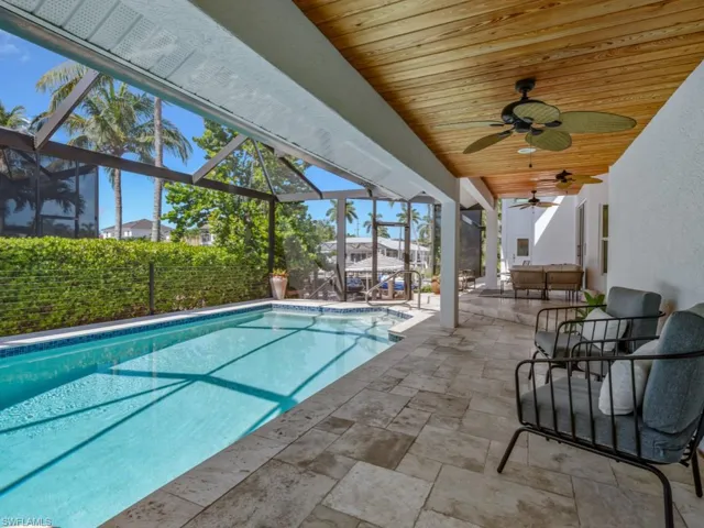 Outdoor pool with a patio, a ceiling fan, glass enclosure, and an outdoor hangout area
