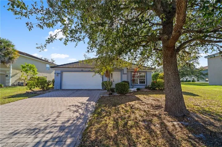 View of front of house featuring decorative driveway, stucco siding, a front lawn, and a garage