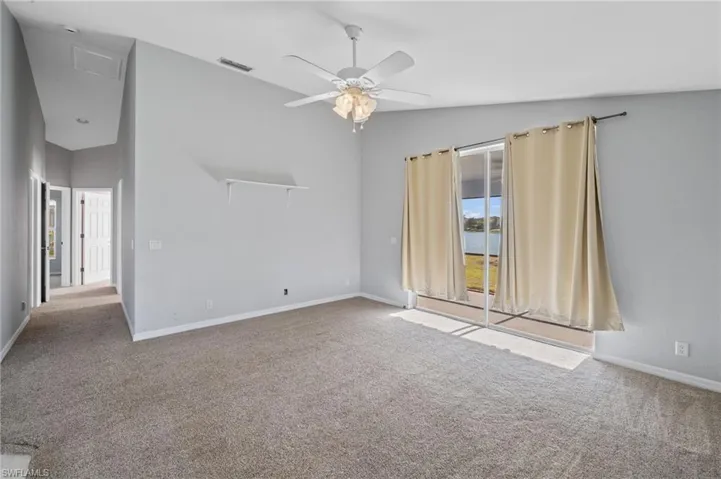 Spare room with vaulted ceiling, carpet flooring, and a ceiling fan