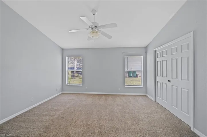 Unfurnished bedroom featuring a closet, light carpet, and a ceiling fan