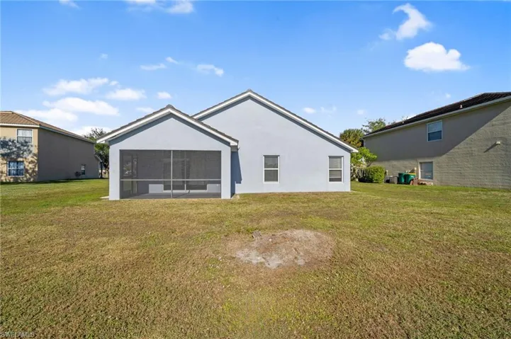 Rear view of house featuring a yard, stucco siding, and a sunroom