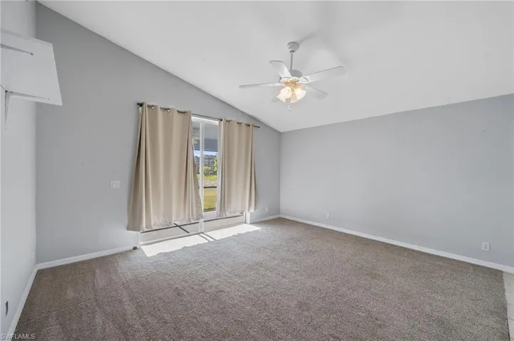 Empty room featuring vaulted ceiling, light colored carpet, and ceiling fan