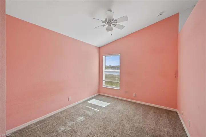 Carpeted empty room with vaulted ceiling and a ceiling fan