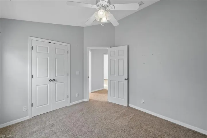 Unfurnished bedroom featuring carpet, a closet, and a ceiling fan