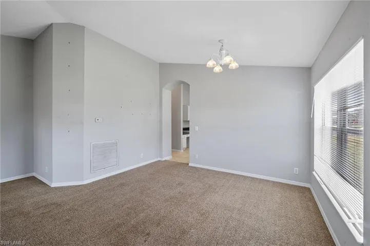 Spare room with carpet, a chandelier, and arched walkways