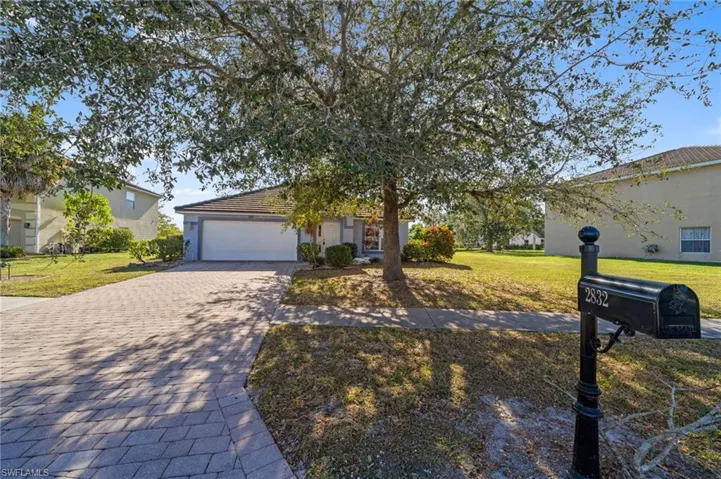 View of front of home with decorative driveway, a front yard, and a garage