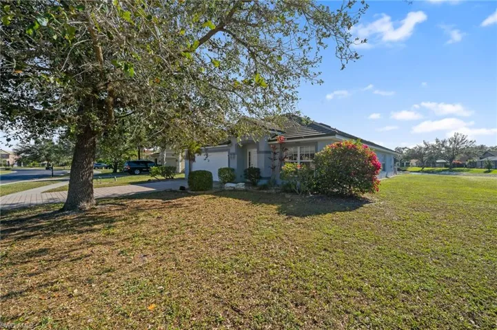 View of side of home with a yard, concrete driveway, and an attached garage