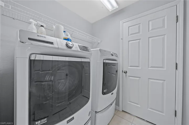 Laundry area featuring light tile patterned floors and separate washer and dryer