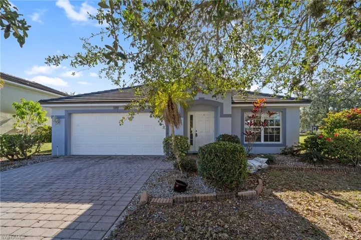 Ranch-style home with decorative driveway, stucco siding, a garage, and a tiled roof