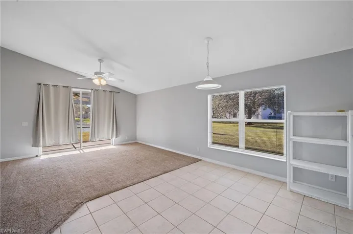 Spare room featuring light colored carpet, vaulted ceiling, and ceiling fan