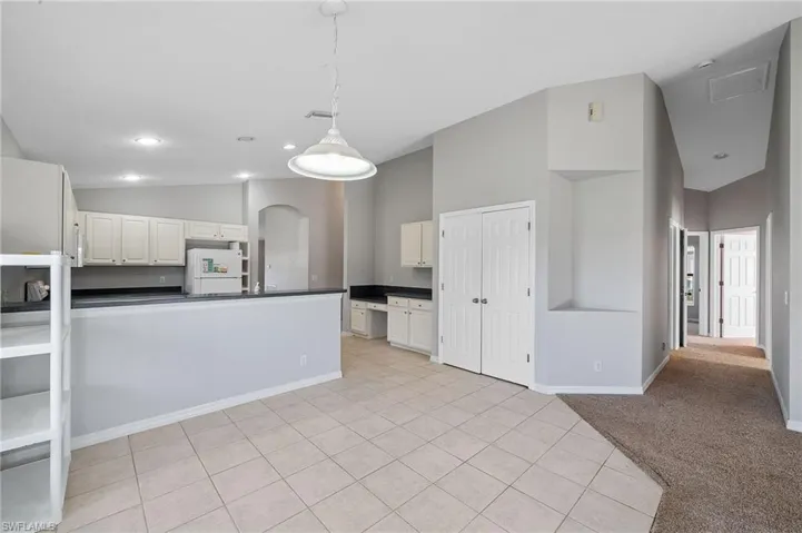 Kitchen featuring a peninsula, dark countertops, decorative light fixtures, freestanding refrigerator, and arched walkways