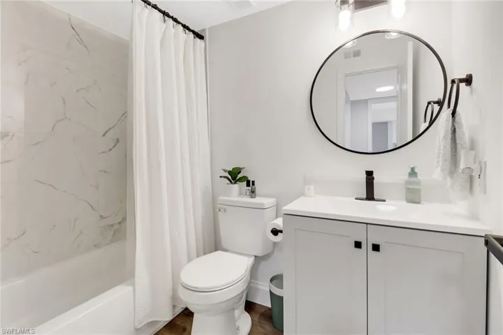 Full bathroom with shower / bath combo, vanity, toilet, and wood-type flooring