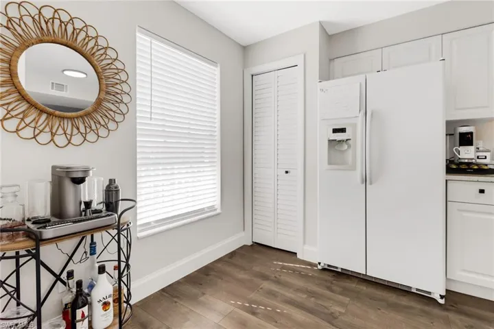 Kitchen with white refrigerator with ice dispenser, white cabinets, and dark wood-type flooring