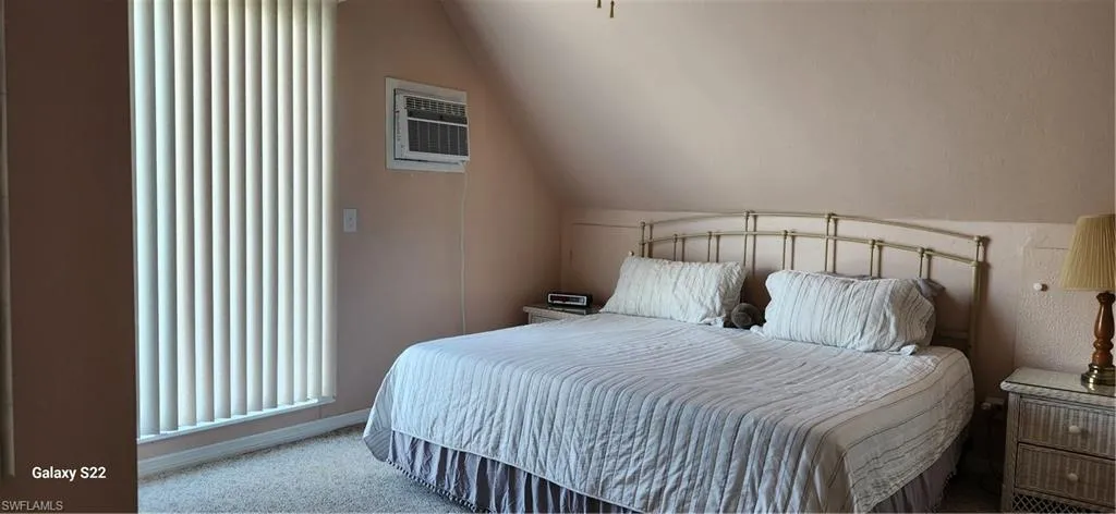 Carpeted bedroom with an AC wall unit and lofted  cealing. With a view of the gulf out your window!