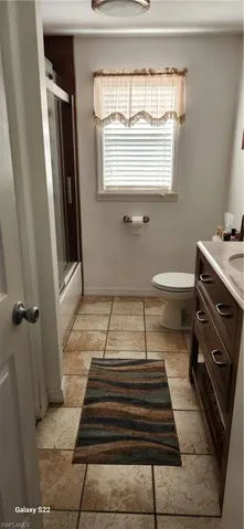 Full bathroom featuring toilet, bath / shower combo with glass door, tile patterned floors, and vanity