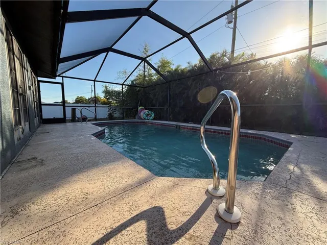 View of pool with glass enclosure and a patio area