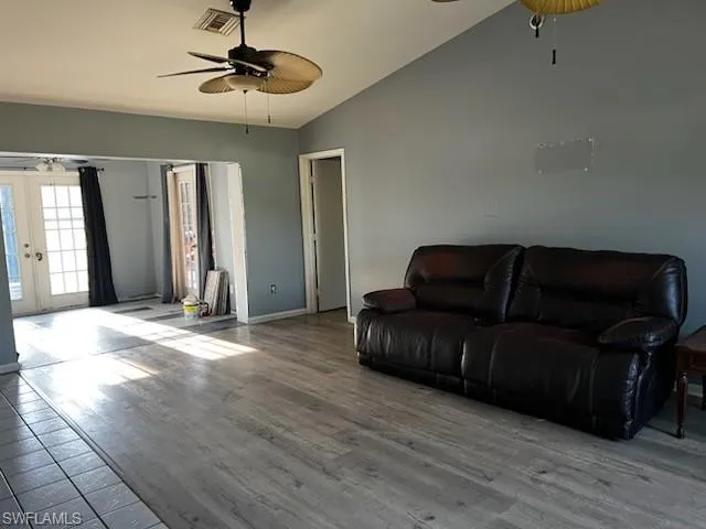 Living room with french doors, lofted ceiling, visible vents, ceiling fan, and wood finished floors