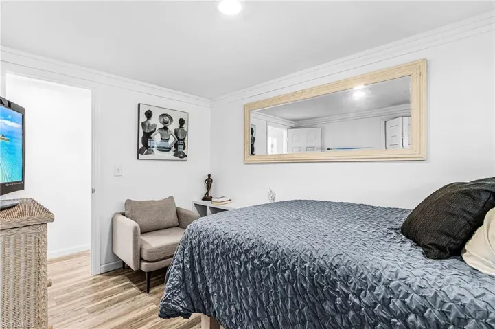 Bedroom with wood finished floors and crown molding