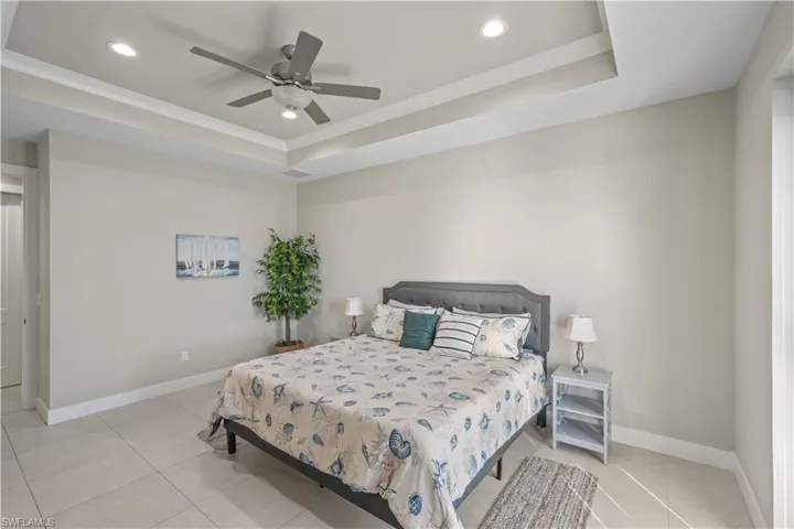 Bedroom featuring a tray ceiling, recessed lighting, a ceiling fan, and light tile patterned floors
