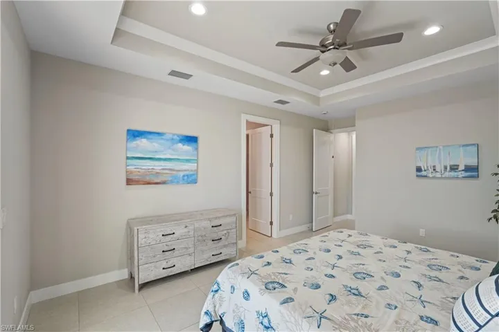 Bedroom with a tray ceiling, a ceiling fan, recessed lighting, and light tile patterned floors