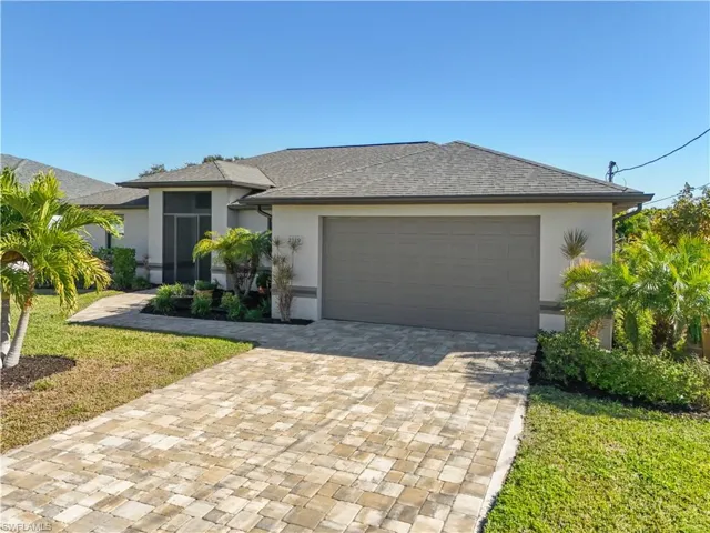 View of front of home featuring stucco siding, decorative driveway, a shingled roof, and a front yard