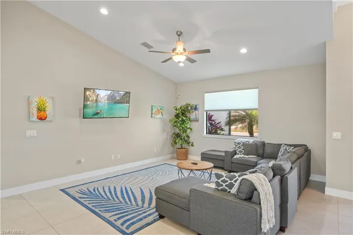Living area featuring light tile patterned flooring, ceiling fan, vaulted ceiling, and recessed lighting