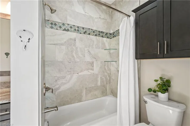 Bathroom with shower / bath combo with shower curtain and toilet