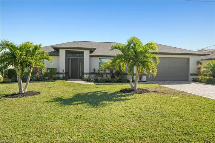 View of front facade with a front lawn, driveway, stucco siding, and an attached garage