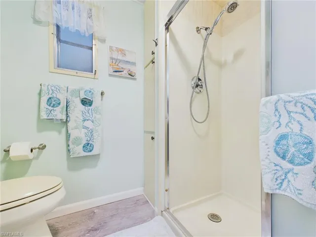 Bathroom featuring a shower with door, toilet, and hardwood / wood-style flooring
