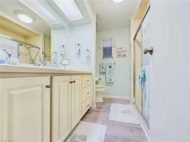 Bathroom featuring a shower with door, toilet, vanity, and hardwood / wood-style flooring