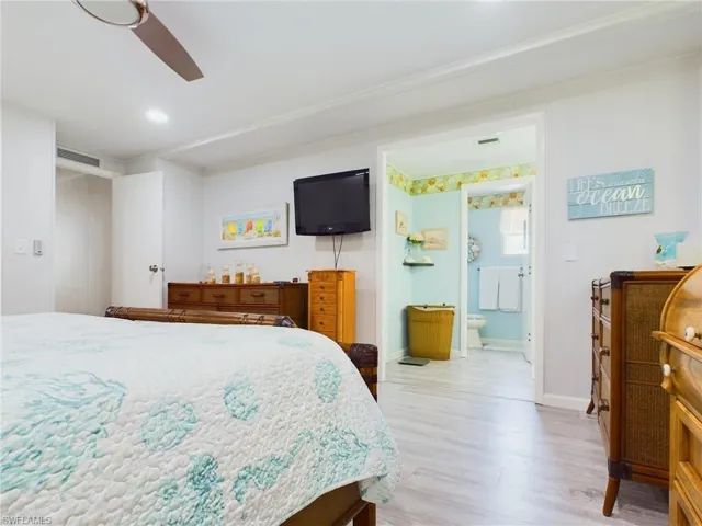 Bedroom featuring ensuite bath, ceiling fan, and light hardwood / wood-style floors