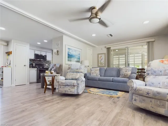Living room with ceiling fan and light hardwood / wood-style flooring