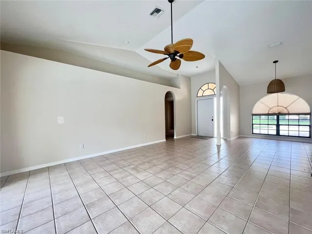 Tiled spare room featuring high vaulted ceiling and ceiling fan