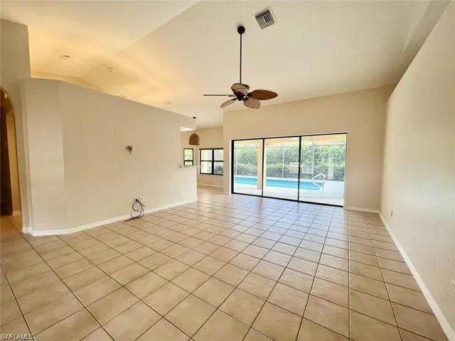 Spare room featuring lofted ceiling, light tile patterned floors, and ceiling fan