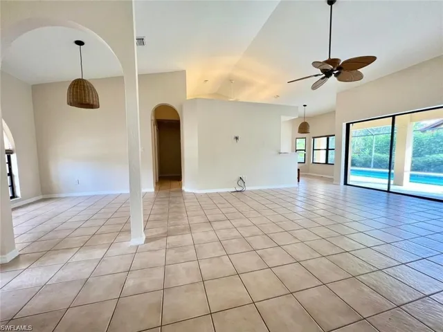 Tiled spare room featuring ceiling fan and high vaulted ceiling