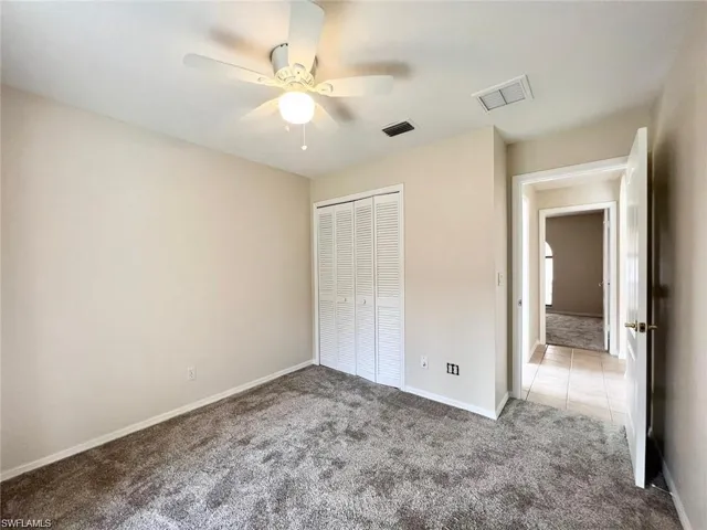 Unfurnished bedroom with carpet, ceiling fan, and a closet