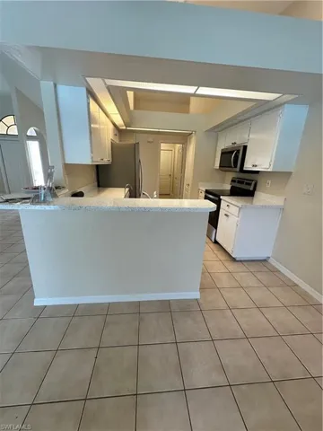 Kitchen with kitchen peninsula, stainless steel fridge with ice dispenser, white cabinetry, dishwasher, and sink